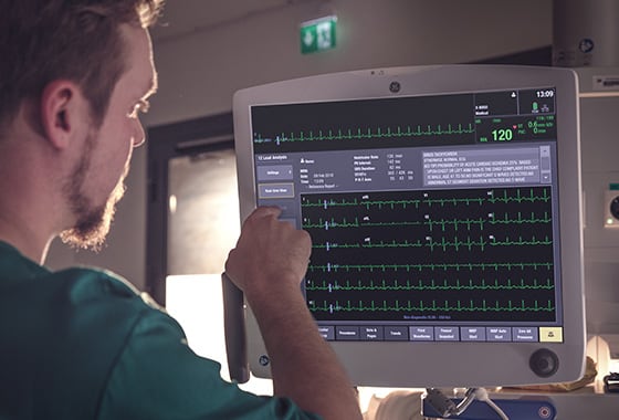 A caregivers is touching on the display screen of a CARESCAPE B850 patient monitor to learn patient data.