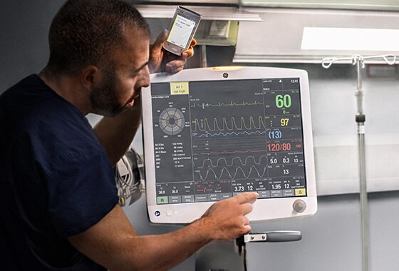 A caregiver is touching on the display screen of a CARESCAPE B850 patient monitor to learn patient data.